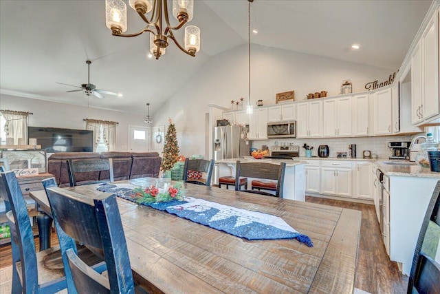 dining room featuring ceiling fan with notable chandelier, wood finished floors, and high vaulted ceiling