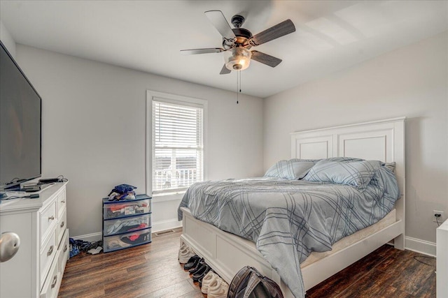 bedroom with dark wood-style floors, a ceiling fan, and baseboards