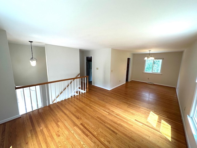 spare room featuring visible vents, baseboards, light wood-type flooring, and a chandelier