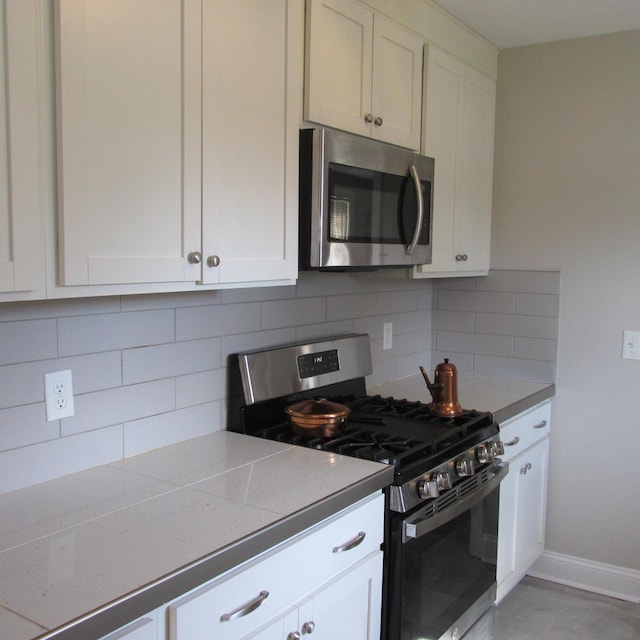 kitchen featuring white cabinets, baseboards, backsplash, and stainless steel appliances