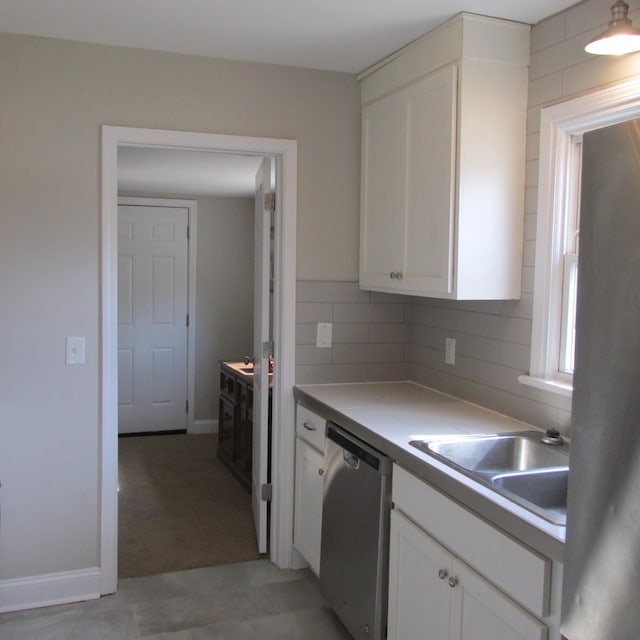 kitchen featuring a sink, decorative backsplash, dishwasher, and white cabinets