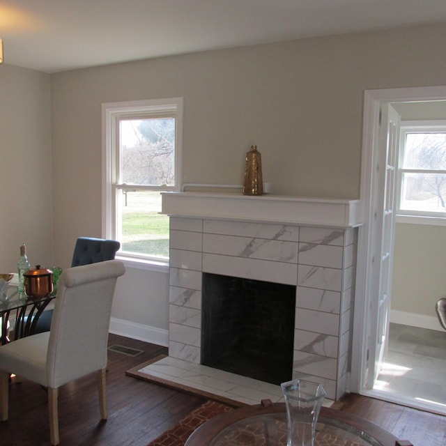 dining space featuring a wealth of natural light, a fireplace, baseboards, and wood finished floors