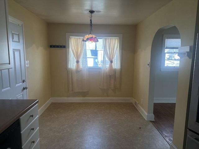 unfurnished dining area featuring arched walkways and baseboards