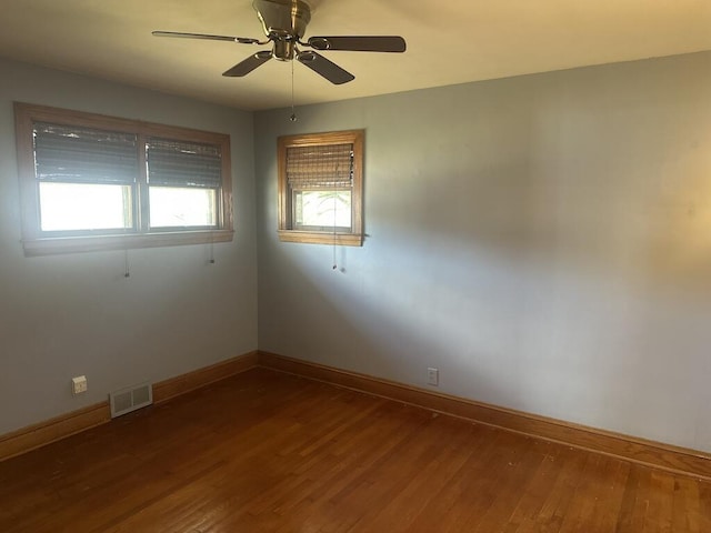 spare room featuring visible vents, ceiling fan, baseboards, and wood finished floors