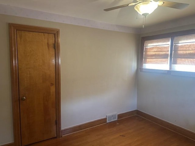 unfurnished room featuring visible vents, a ceiling fan, baseboards, and wood finished floors