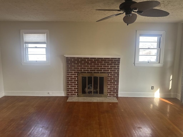 unfurnished living room featuring hardwood / wood-style floors, a healthy amount of sunlight, a fireplace, and a textured ceiling