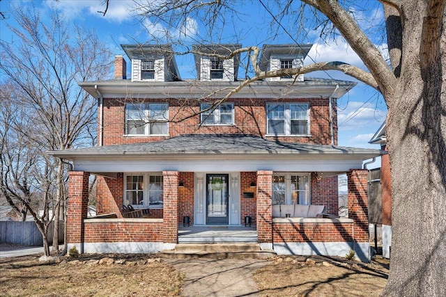 traditional style home featuring brick siding, a porch, and fence