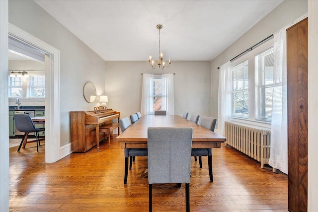 dining space with a chandelier, radiator, baseboards, and wood-type flooring