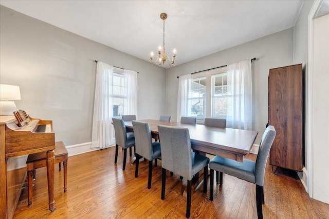 dining area with a notable chandelier, light wood-style flooring, and baseboards