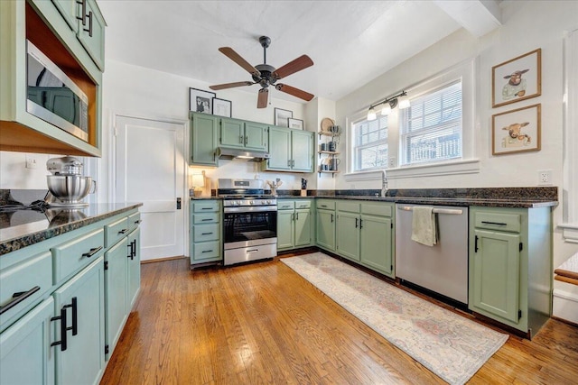 kitchen with light wood-type flooring, a ceiling fan, open shelves, appliances with stainless steel finishes, and green cabinets