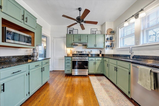 kitchen featuring green cabinetry, a sink, ceiling fan, under cabinet range hood, and appliances with stainless steel finishes