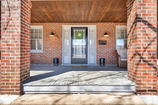 entrance to property featuring covered porch and brick siding