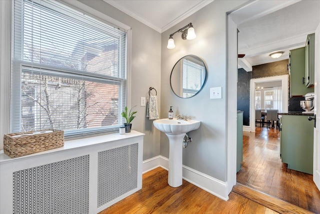 bathroom featuring baseboards, wood-type flooring, ornamental molding, and radiator heating unit