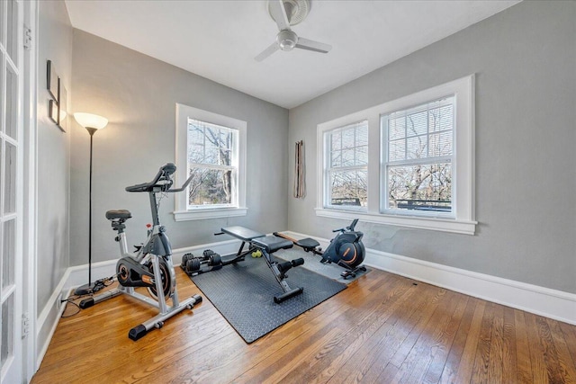 workout room with a ceiling fan, light wood-type flooring, and baseboards