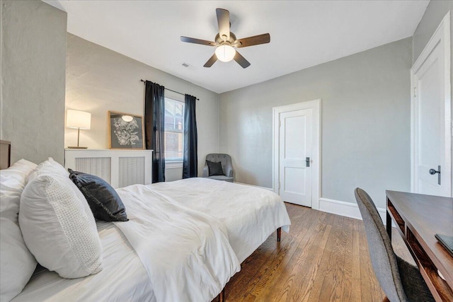 bedroom with visible vents, a ceiling fan, baseboards, and wood finished floors