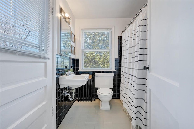 full bathroom with tile patterned floors, a wainscoted wall, toilet, a shower with shower curtain, and tile walls