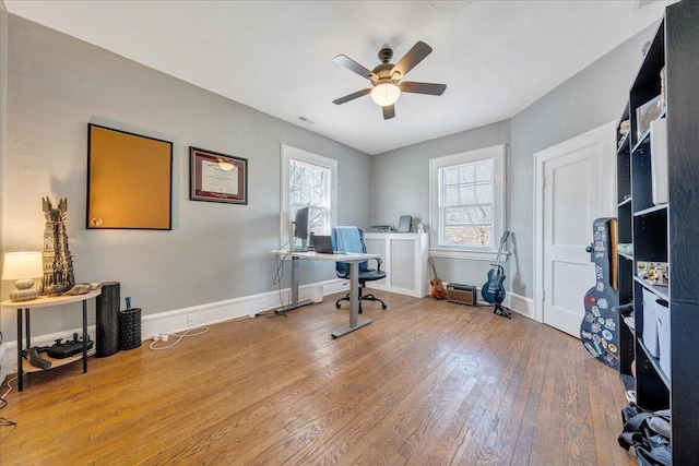 office area featuring hardwood / wood-style flooring, a ceiling fan, baseboards, and visible vents