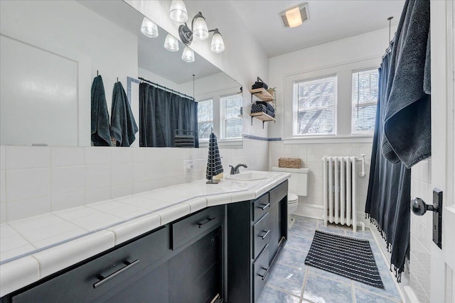 full bath with radiator, toilet, vanity, a shower with curtain, and tile walls