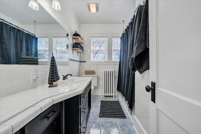 bathroom with vanity, a shower with shower curtain, visible vents, radiator heating unit, and tile walls