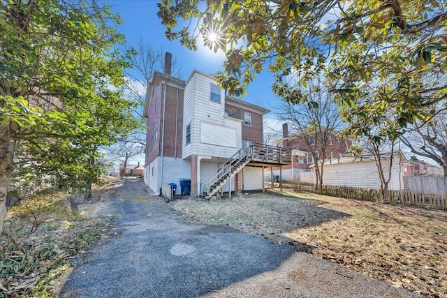 back of house with a chimney, stairs, and fence