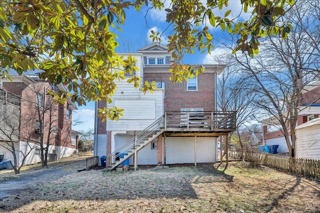 back of house featuring stairway, brick siding, a wooden deck, and fence