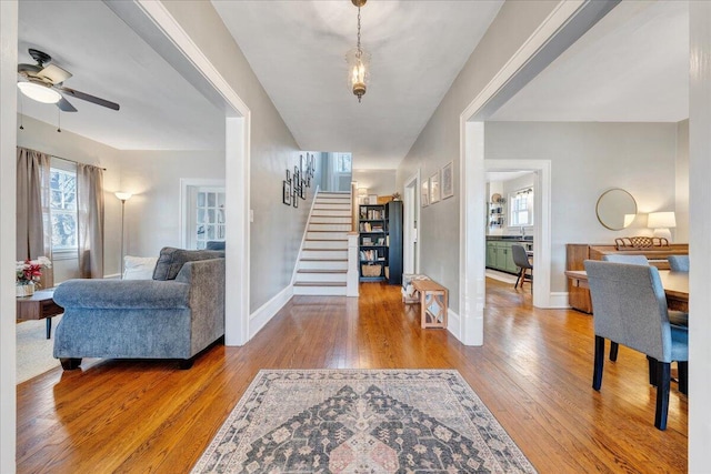 entryway with baseboards, a ceiling fan, hardwood / wood-style floors, and stairs