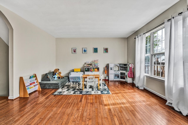 playroom with hardwood / wood-style flooring, arched walkways, and baseboards