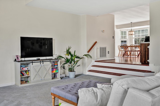 living area featuring visible vents, baseboards, stairs, carpet floors, and a notable chandelier