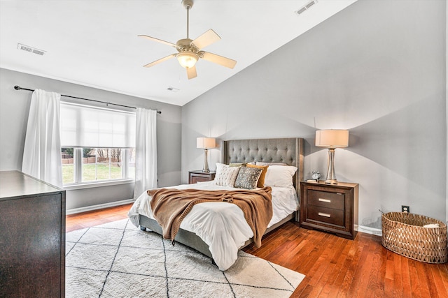 bedroom with vaulted ceiling, wood finished floors, visible vents, and baseboards