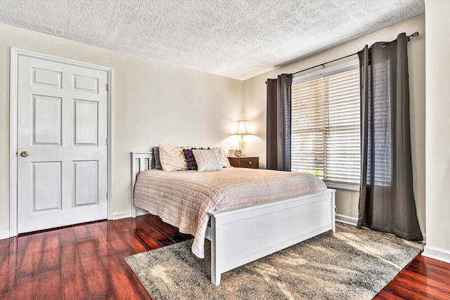 bedroom featuring wood finished floors, baseboards, and a textured ceiling