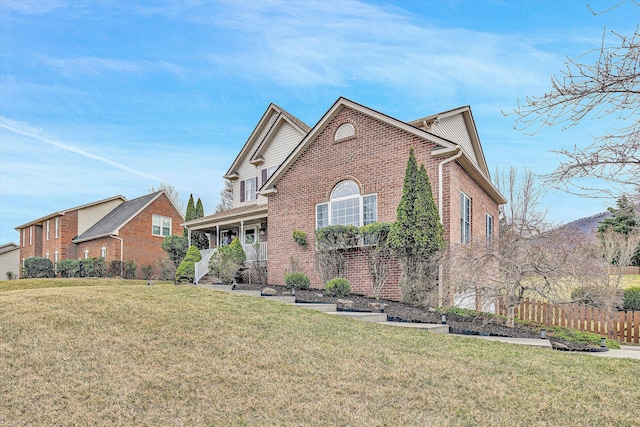 traditional-style house with a front lawn, a porch, fence, and brick siding