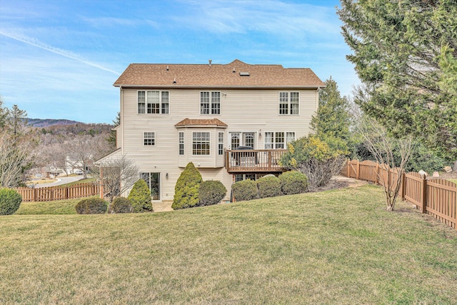 back of property with a yard, a deck, a shingled roof, and a fenced backyard