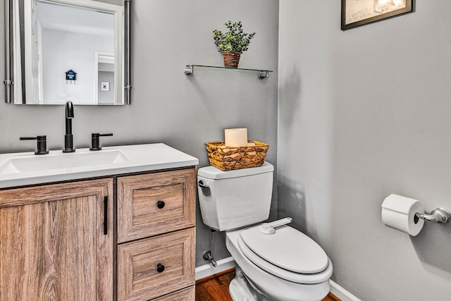 bathroom featuring vanity, toilet, wood finished floors, and baseboards