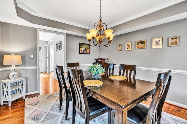 dining space with light wood finished floors, baseboards, an inviting chandelier, and ornamental molding