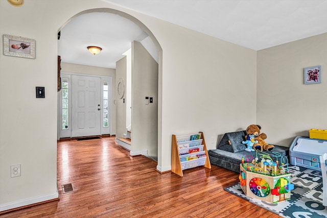 foyer entrance featuring hardwood / wood-style flooring, baseboards, and arched walkways