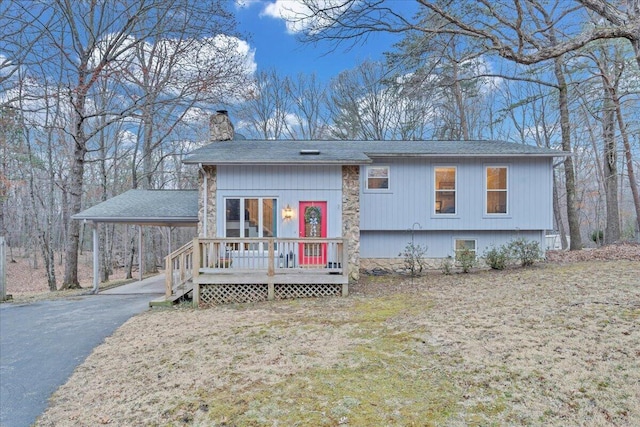 view of front facade featuring aphalt driveway, a front lawn, an attached carport, and a chimney