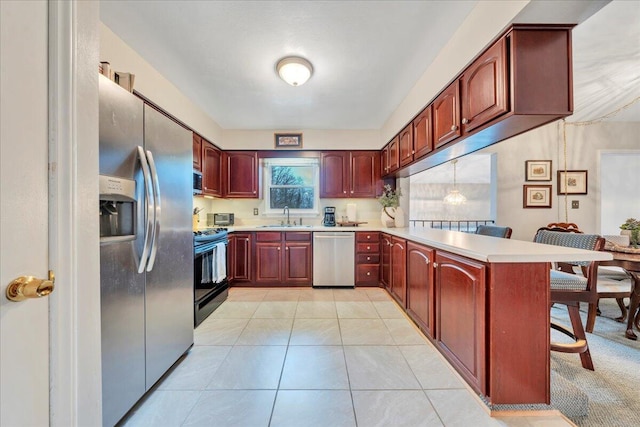 kitchen with dark brown cabinets, light countertops, light tile patterned floors, appliances with stainless steel finishes, and a peninsula