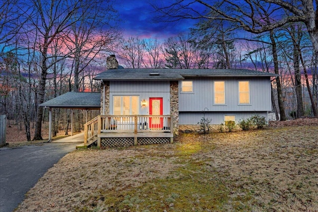 view of front of house featuring aphalt driveway, a chimney, and a carport