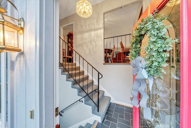 staircase with baseboards and a notable chandelier