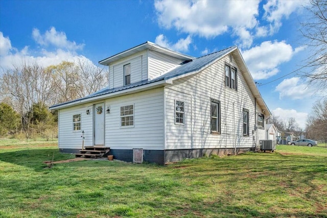 back of house featuring a lawn, metal roof, central AC unit, and entry steps