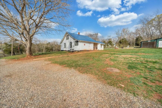 view of side of property with central AC unit, a lawn, a chimney, and gravel driveway