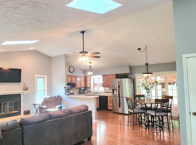 7167 Bent Mountain Rd, Roanoke, VA 24018 - living room with wood finished floors, ceiling fan, a glass covered fireplace, a textured ceiling, and lofted ceiling with skylight