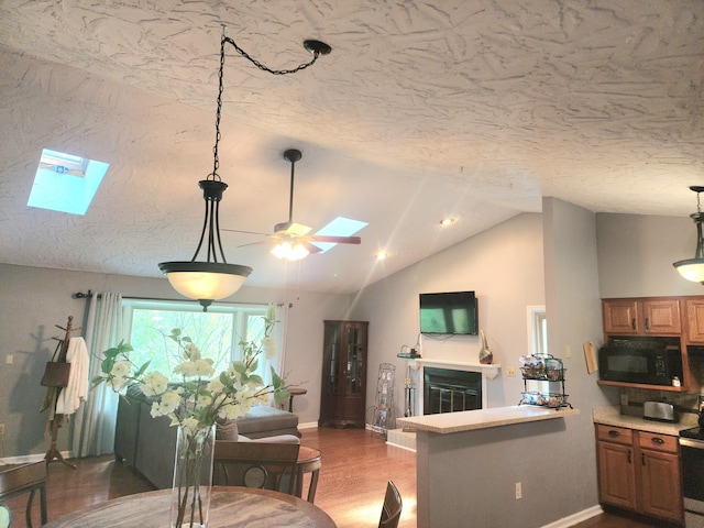 7167 Bent Mountain Rd, Roanoke, VA 24018 - kitchen with vaulted ceiling with skylight, black microwave, baseboards, a glass covered fireplace, and a ceiling fan
