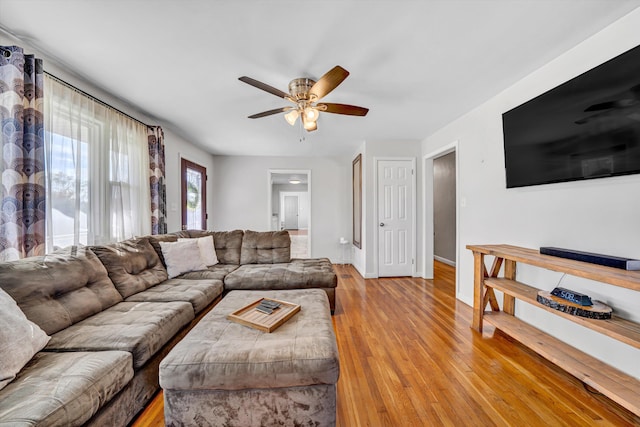 living area featuring baseboards, a ceiling fan, and light wood-style floors