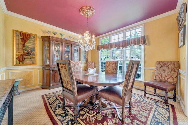 dining area with ornamental molding, a decorative wall, an inviting chandelier, and a wainscoted wall