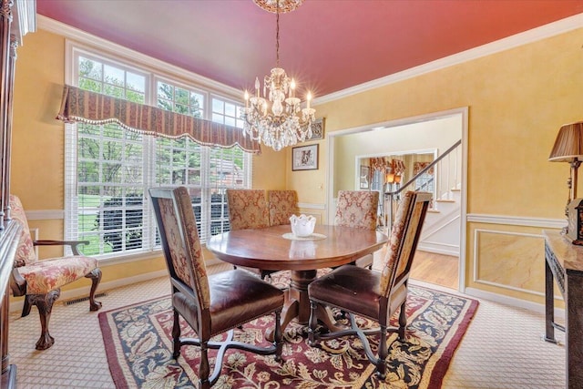 dining area with wainscoting, crown molding, a notable chandelier, and carpet floors