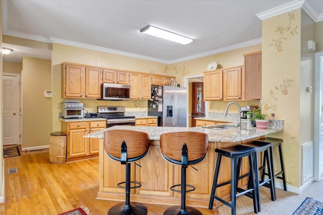 kitchen with a sink, a peninsula, stainless steel appliances, crown molding, and light wood-style flooring