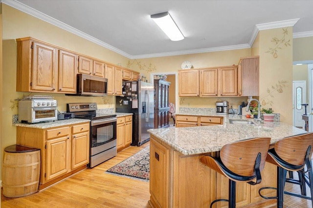 kitchen with ornamental molding, a peninsula, appliances with stainless steel finishes, and a sink