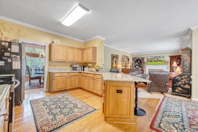 kitchen with a breakfast bar, ornamental molding, open floor plan, a peninsula, and light wood-type flooring