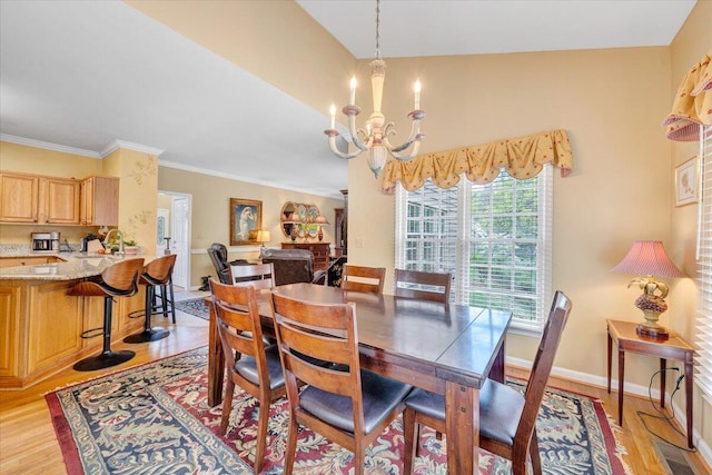 dining area featuring ornamental molding, a notable chandelier, baseboards, and light wood-style floors